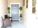 Inviting front porch with blue door, blue rug, wicker chairs, and decorative hanging plants at 30798 Veridian Way, Wesley Chapel, FL 33543