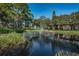 Scenic view of a pond with a fountain, surrounded by lush greenery and mature trees under a bright blue sky at 5265 E Bay Dr # 521, Clearwater, FL 33764