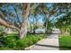 Landscaped walkway leading to a gated community entrance, framed by mature trees and lush greenery, with a pond fountain at 5265 E Bay Dr # 521, Clearwater, FL 33764