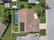 Aerial view of a home with a screened pool, solar panels, and a fenced yard at 7022 Kingsway Dr, Port Richey, FL 34668