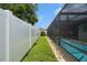 Manicured backyard features grass with privacy fence and access to the screened-in pool at 7022 Kingsway Dr, Port Richey, FL 34668