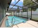Outdoor pool with screened enclosure, seating, and a clear blue sky above at 7022 Kingsway Dr, Port Richey, FL 34668