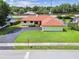 Aerial view of a lovely home with a red roof, a long driveway, and a well-maintained lawn at 855 Pinewood W Ter, Palm Harbor, FL 34683