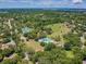 A sprawling aerial view showcasing community amenities including tennis courts and a pool, set amidst lush greenery and trees at 855 Pinewood W Ter, Palm Harbor, FL 34683