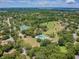 A sprawling aerial view showcasing community amenities including tennis courts and a pool, set amidst lush greenery and trees at 855 Pinewood W Ter, Palm Harbor, FL 34683