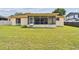 View of backyard showing the screened in back patio and home with tidy landscaping at 855 Pinewood W Ter, Palm Harbor, FL 34683