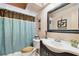 Well-lit bathroom featuring a vanity with a large mirror and a shower with a decorative blue curtain at 855 Pinewood W Ter, Palm Harbor, FL 34683