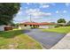 Charming single-story home with a red roof, lush landscaping, and a spacious driveway leading to an attached garage at 855 Pinewood W Ter, Palm Harbor, FL 34683