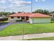 Single story home featuring a red roof, green lawn, and an attached garage at 855 Pinewood W Ter, Palm Harbor, FL 34683