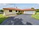 Charming single-story home with a red roof, lush landscaping, and a spacious driveway leading to an attached garage at 855 Pinewood W Ter, Palm Harbor, FL 34683
