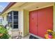 Charming home entrance with a vibrant front door, blooming flowers, and a bay window at 855 Pinewood W Ter, Palm Harbor, FL 34683