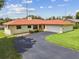 Beautiful single-story home with a red roof, a driveway, and a lush green lawn enhancing its appeal at 855 Pinewood W Ter, Palm Harbor, FL 34683