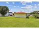 Side view of home highlighting a garage, with a well-manicured lawn and sunny skies at 855 Pinewood W Ter, Palm Harbor, FL 34683