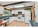 Bright kitchen features white cabinets, modern appliances, dark wood beams, and tile floors at 855 Pinewood W Ter, Palm Harbor, FL 34683
