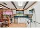 Bright eat-in kitchen features white cabinets, modern appliances, dark wood beams, and tile floors at 855 Pinewood W Ter, Palm Harbor, FL 34683