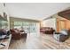 A spacious living room with hardwood floors, comfortable seating, and sliding glass doors to the outside at 855 Pinewood W Ter, Palm Harbor, FL 34683