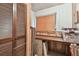 Storage room featuring a work desk, slat doors, wooden paneled walls and tile floors at 855 Pinewood W Ter, Palm Harbor, FL 34683