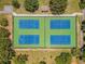 Aerial view of four well-maintained community tennis courts surrounded by mature trees and landscaping at 855 Pinewood W Ter, Palm Harbor, FL 34683