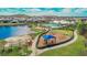 Aerial view of a community with a pool, playground, lake, and clubhouse, surrounded by homes and greenery at 11019 Leland Groves Dr, Riverview, FL 33579