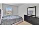 Cozy bedroom featuring a comfortable bed with a gray comforter, a sleek dresser, and a window with natural light at 11019 Leland Groves Dr, Riverview, FL 33579
