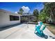 A backyard featuring an enclosed patio, chairs, greenery, and a spacious yard at 112 Peterson Ln, Palm Harbor, FL 34683