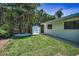 A lush backyard with a storage shed, a lawn, and tropical landscaping provides a serene outdoor space at 112 Peterson Ln, Palm Harbor, FL 34683