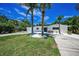 Inviting home featuring a lush lawn, tropical landscaping, and a circular driveway at 112 Peterson Ln, Palm Harbor, FL 34683
