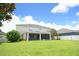 Large backyard featuring a covered, screened porch with a spacious lawn, lush landscaping, and a bright blue sky at 11408 Scribner Station Ln, Lithia, FL 33547