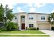 Beige two-story home with a well-manicured lawn, two-car garage, and mature landscaping at 11408 Scribner Station Ln, Lithia, FL 33547