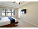 Primary bedroom featuring ceiling fan, wall-mounted TV, and sliding glass door at 11408 Scribner Station Ln, Lithia, FL 33547