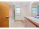 Bathroom with pink tile, neutral flooring, toilet, sink, vanity, window, shower and tropical print shower curtain at 12546 Brookside St, Spring Hill, FL 34609