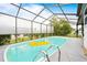 Screened-in pool with yellow raft and ladder surrounded by neutral colored patio and a view of shrubbery and blue skies at 12546 Brookside St, Spring Hill, FL 34609