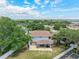 Aerial view of a backyard with a covered patio, lush lawn, and mature trees, with room for outdoor activities at 1291 Blackrush Dr, Tarpon Springs, FL 34689