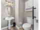 Stylish half-bathroom with a pedestal sink, oval mirror, modern lighting, and wood-look flooring at 1291 Blackrush Dr, Tarpon Springs, FL 34689