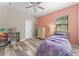 Bedroom featuring peach accent wall, toys, and wood-look floors at 1291 Blackrush Dr, Tarpon Springs, FL 34689