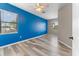 Bedroom with a bright blue accent wall, ceiling fan, and wood-look floors at 1291 Blackrush Dr, Tarpon Springs, FL 34689