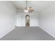 Open main bedroom with carpet, ceiling fan, and hallway access with arched doorways at 14006 Amero Ln, Spring Hill, FL 34609