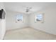 Well-lit bedroom featuring carpet floors, two windows, and a ceiling fan at 17025 Dolphin Dr, North Redington Beach, FL 33708