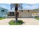 Tan two-story home with a palm tree in the front yard and a two-car garage at 17025 Dolphin Dr, North Redington Beach, FL 33708
