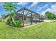 A backyard with a screened-in pool area, lush greenery, and a well-manicured lawn at 1830 Cameron Ct, Trinity, FL 34655