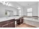 Bright bathroom featuring dual sinks, dark wood cabinets, a large mirror, and a soaking tub at 1830 Cameron Ct, Trinity, FL 34655