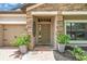 Close-up of the front entrance, featuring a stone surround, brick walkway, and potted plants at 1830 Cameron Ct, Trinity, FL 34655