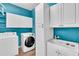Bright laundry room with blue walls, white cabinets, a utility sink, and modern washer and dryer at 1830 Cameron Ct, Trinity, FL 34655
