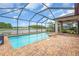 Screened-in pool area with brick pavers, a view of a lake, and an outdoor ceiling fan at 1830 Cameron Ct, Trinity, FL 34655