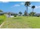 Home's backyard featuring a large grass area and palm trees, and other homes in the neighborhood at 1903 Canterbury Ln # B24, Sun City Center, FL 33573