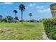 Backyard featuring large grass area, palm trees, with other homes in the background at 1903 Canterbury Ln # B24, Sun City Center, FL 33573