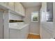 Bright laundry room with washer, dryer, storage cabinets, and natural light from a window at 1903 Canterbury Ln # B24, Sun City Center, FL 33573