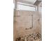 Shower stall with gray tile surround, pebble floor, a shower head, and glass shelving at 2559 Redwood Cir, Clearwater, FL 33763
