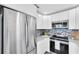 Well-equipped kitchen featuring stainless steel refrigerator, white cabinets, and mosaic backsplash, blending style and functionality at 2900 45Th S St # 26, Gulfport, FL 33711