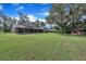 Expansive backyard featuring a covered patio, a bar shed, mature trees, and lush green grass at 302 Old Mulrennan Rd, Valrico, FL 33594